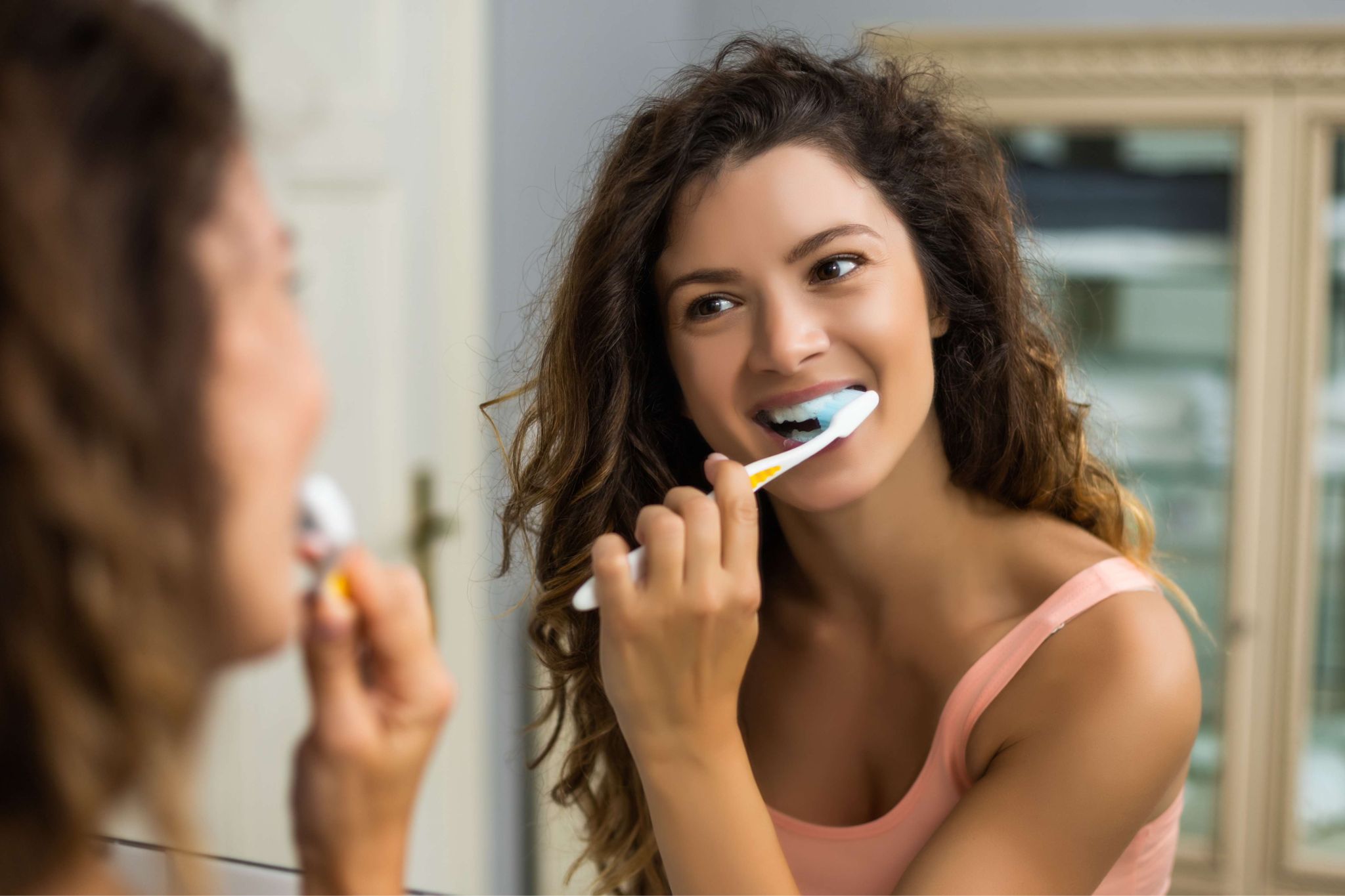 Woman brushing teeth maintaining oral hygiene after professional teeth whitening